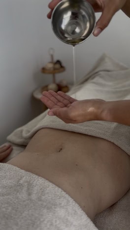 femme qui applique de l'huile sur le ventre d'une femme