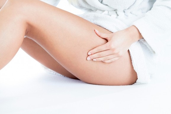 Cuisses d'une femme se pinçant la cellulite