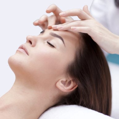 Visage d'une femme se faisant masser par une esthéticienne