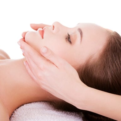 Femme allongée sur une table de massage, une esthéticienne lui masse le visage