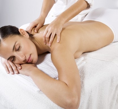 Femme allongée sur le ventre se faisant masser par une esthéticienne