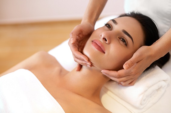 Une femme se fait masser le visage, gros plant sur les mains.
