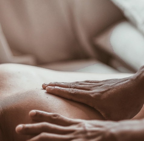 Dos d'une femme qui se fait masser par les deux mains d'une thérapeute.