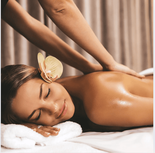 femme qui reçoit un masage polynésien allongée sur le ventre avec un fleur de tiaré